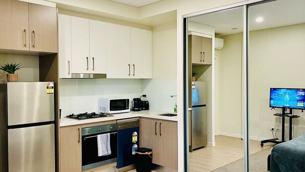 Een moderne keuken met roestvrijstalen apparatuur, houten kastjes en een klein eetgedeelte met een televisie.
