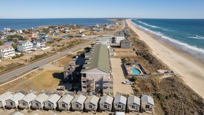 A coastal hotel with multiple-story buildings, a swimming pool, and beach access. - Oceanfront Condo, Beach Access, Shared Pool, & Hot Tub (Hatteras)