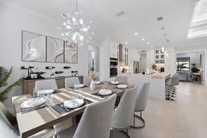 Una cocina moderna con armarios blancos, una isla central y un comedor con una mesa grande para seis comensales.