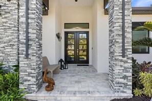 A modern house entrance with a stone facade, a dark double door, and a bench outside. - Modern Coastal Escape with Private Heated Saltwater Pool&Spa-Minutes to Beaches (Nokomis)