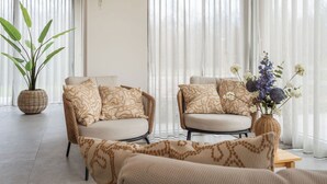 A cozy living room with two wicker sofas, patterned cushions, a large potted plant, and a vase with flowers. - De Ruiser by Interhome (Biggekerke)