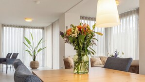A modern dining area with a wooden table, chairs, and a vase of flowers. - De Ruiser by Interhome (Biggekerke)