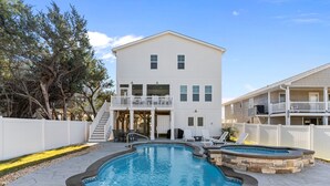Une maison à deux étages avec une piscine, un patio couvert et une cour arrière clôturée.
