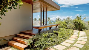 A modern outdoor staircase leading to a wooden deck with a view of palm trees and a clear sky. - Alma Maraú  (Maraú)