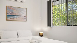 Ett hotellrum med en säng, en tavla, ett fönster med galler och en lampa.