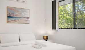 A hotel room with a bed, a painting, a window with bars, and a lamp. - Cabramatta | Spacious 3 Bedroom Family Townhouse (Cabramatta)