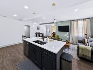 A modern kitchen with a central island, black cabinets, and a white countertop. - Historic Avondale 5BR | Porch, Grill & Parking (Jacksonville)