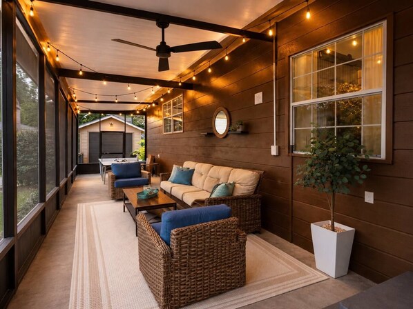 A covered outdoor seating area with wicker furniture, a ceiling fan, and string lights. - Historic Avondale 5BR | Porch, Grill & Parking (Jacksonville)