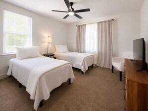 A hotel room with two beds, a ceiling fan, a TV, and a desk. - Historic Avondale 5BR | Porch, Grill & Parking (Jacksonville)