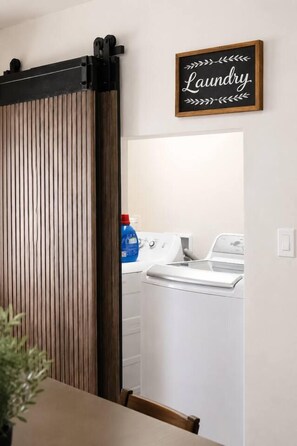 A laundry area with a wooden sliding door and a sign above it. - Historic Avondale 5BR | Porch, Grill & Parking (Jacksonville)