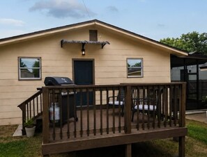 A single-story house with a front deck, a barbecue grill, and a small porch with two chairs. - Historic Avondale 5BR | Porch, Grill & Parking (Jacksonville)
