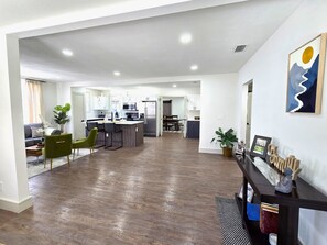 Ein moderner Wohnraum mit Küche, Essbereich und einem Flur, der zu den Schlafzimmern führt.