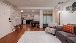 Una sala de estar moderna con un sofá gris, un sillón estampado y un comedor con mesa y sillas.