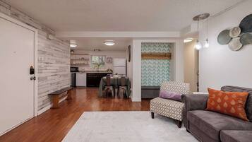 A modern living room with a grey sofa, a patterned armchair, and a dining area with a table and chairs.