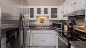 A compact kitchen with white cabinets, stainless steel appliances, and a microwave. - Cozy South Addition Downtown Getaway - King Beds (Anchorage)