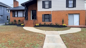 A two-story house with a brick facade, a front porch, and a driveway leading to the entrance.
