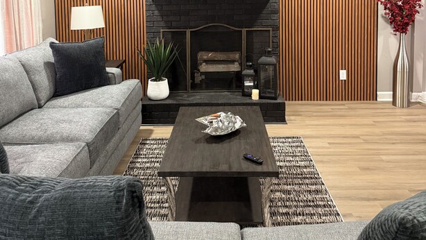A modern living room with a sofa, a coffee table, a fireplace, and a ceiling fan.