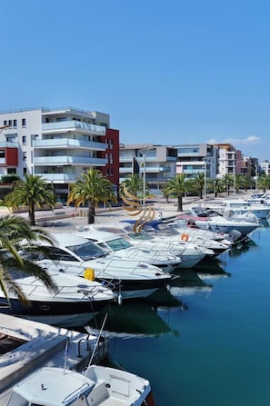 A marina with several boats docked, surrounded by modern buildings and palm trees. - NewPort Riviera T3, Terrace, Clim, Garage, Wifi (Fréjus)