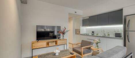 A modern living room with a flat-screen TV, wooden furniture, and a grey sofa.