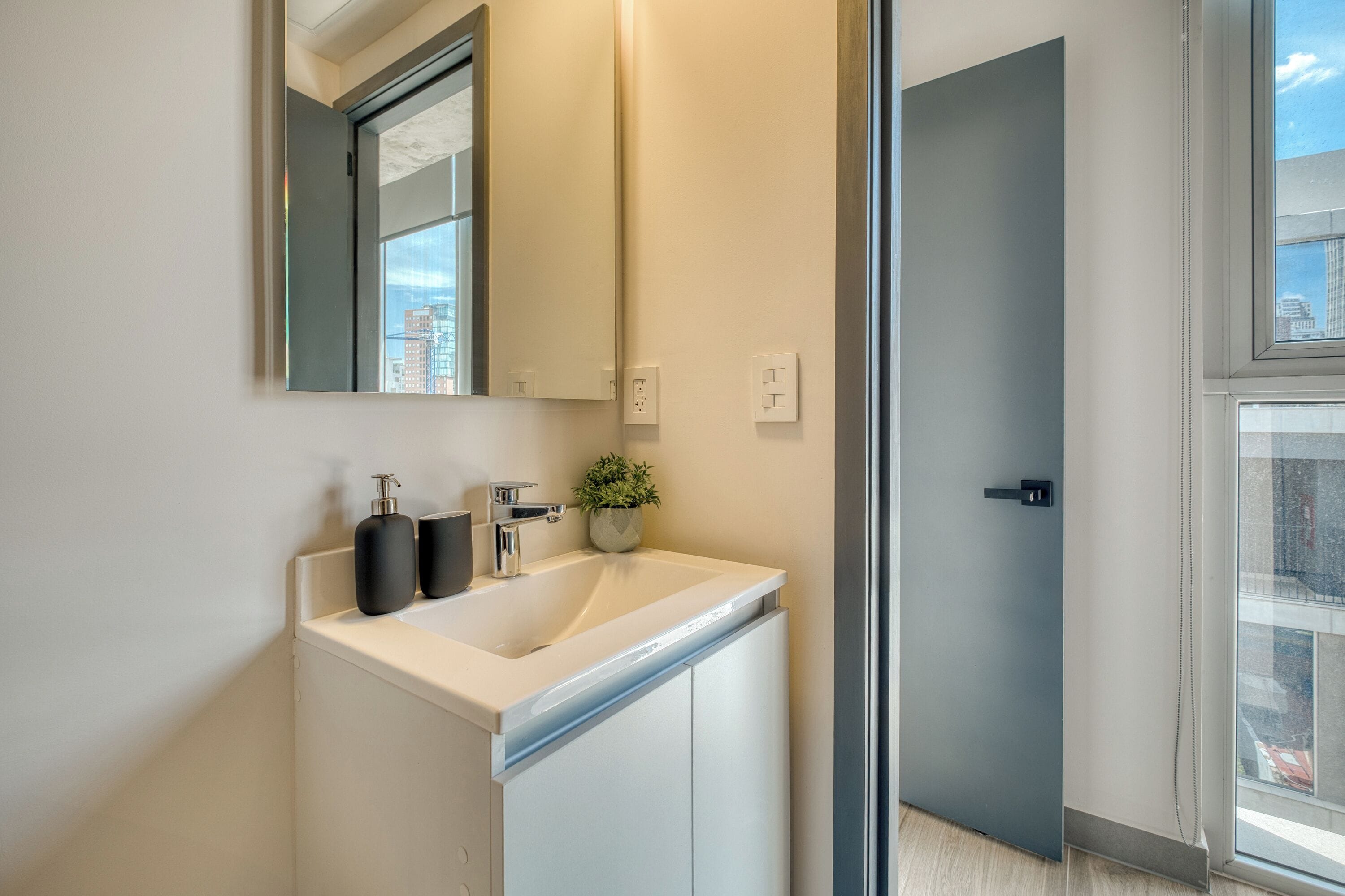 Een moderne badkamer met een wit wastafel, een spiegel en een potplant.