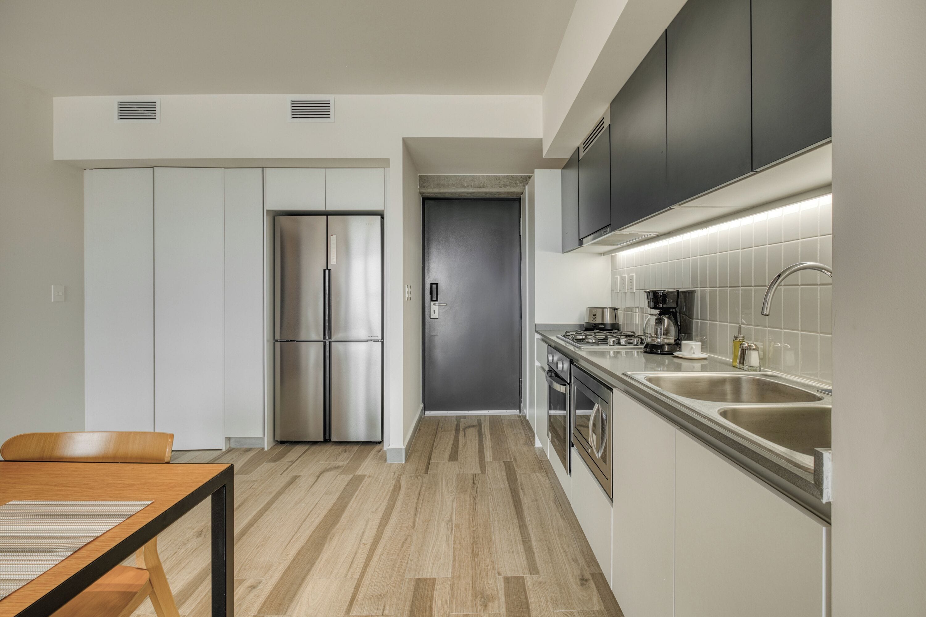 A modern kitchen with a stainless steel refrigerator, a built-in oven, and a double sink.