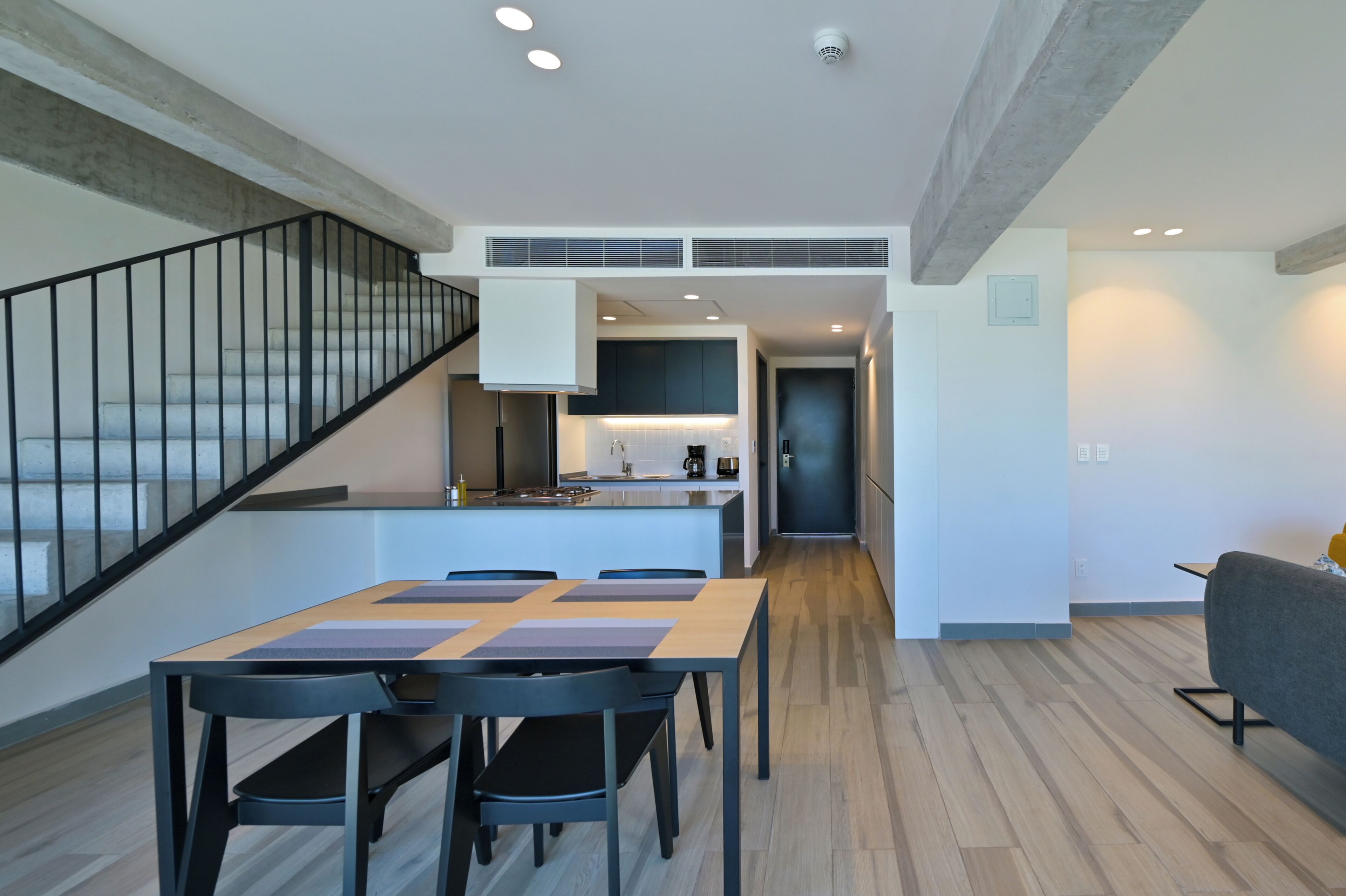 Une cuisine moderne dotée d’un îlot central, d’un coin repas avec une table et des chaises, et d’un escalier avec une rampe.