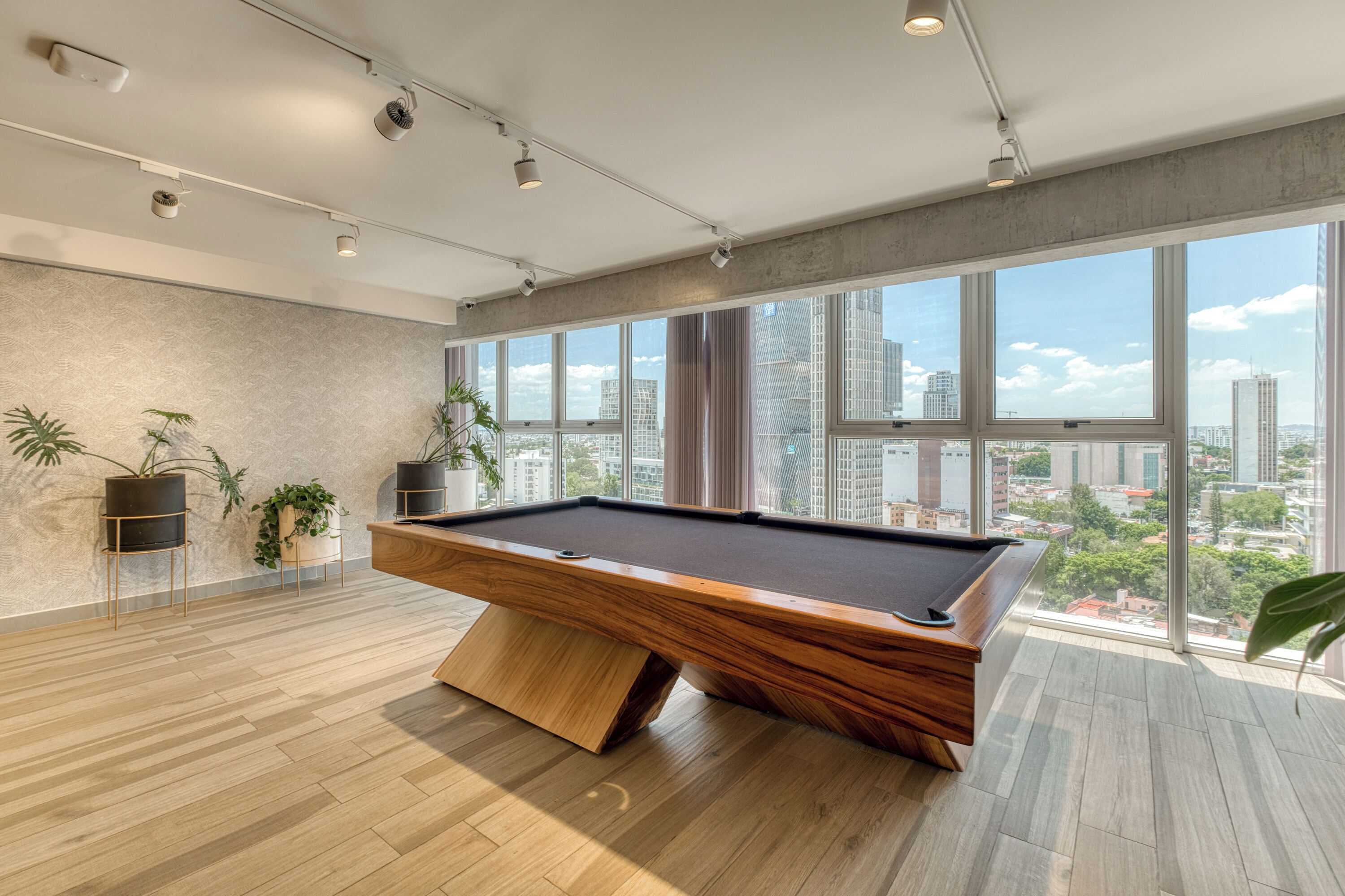A modern indoor pool table in a spacious room with large windows offering a city view.
