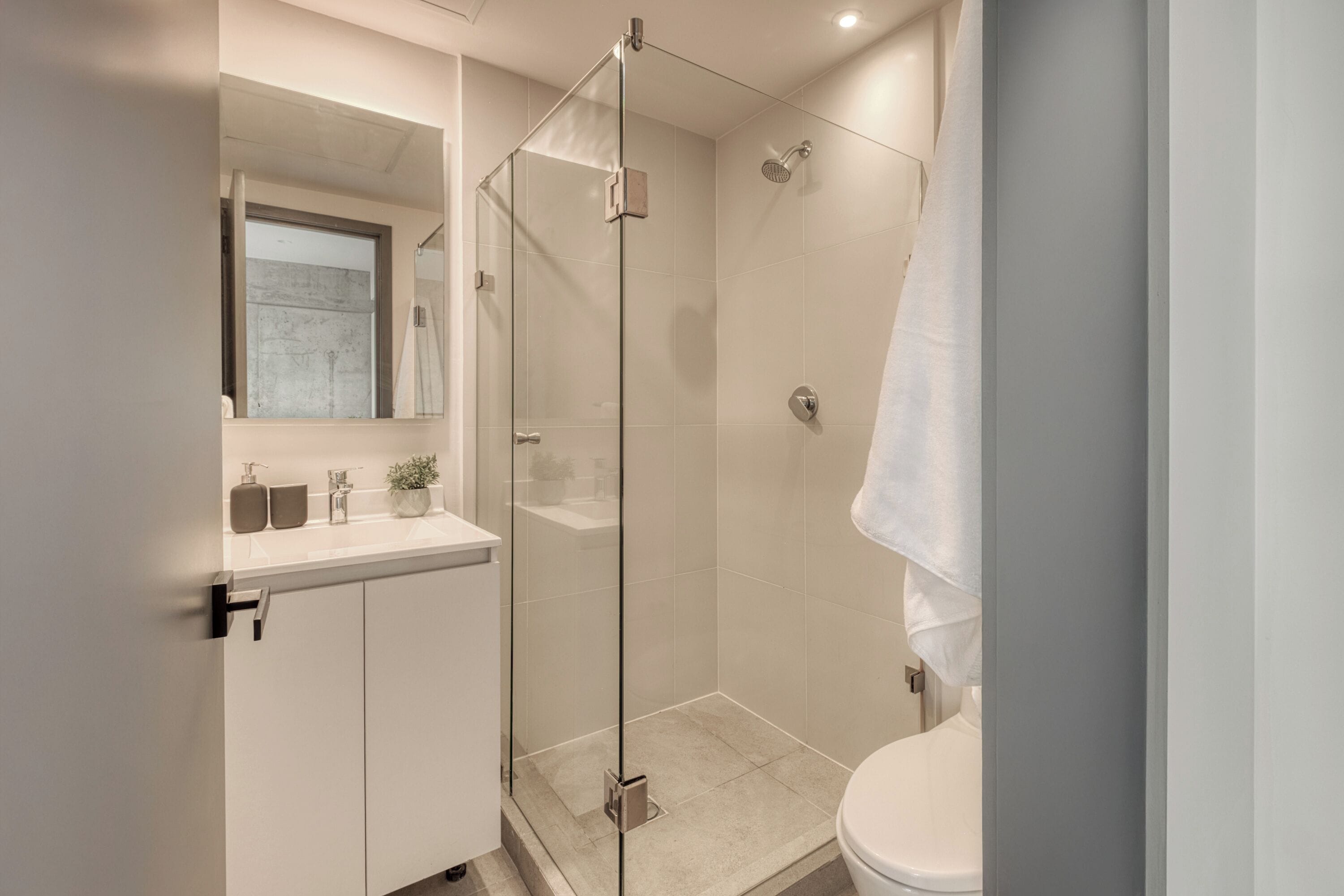 Ein modernes Badezimmer mit einer Duschkabine, einem weißen Waschbecken und einer Toilette.