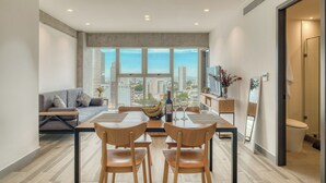 A modern living room with a dining area, large windows with a city view, a sofa, and a coffee table. - Nido Nomad Pablo Neruda GDL (Guadalajara)