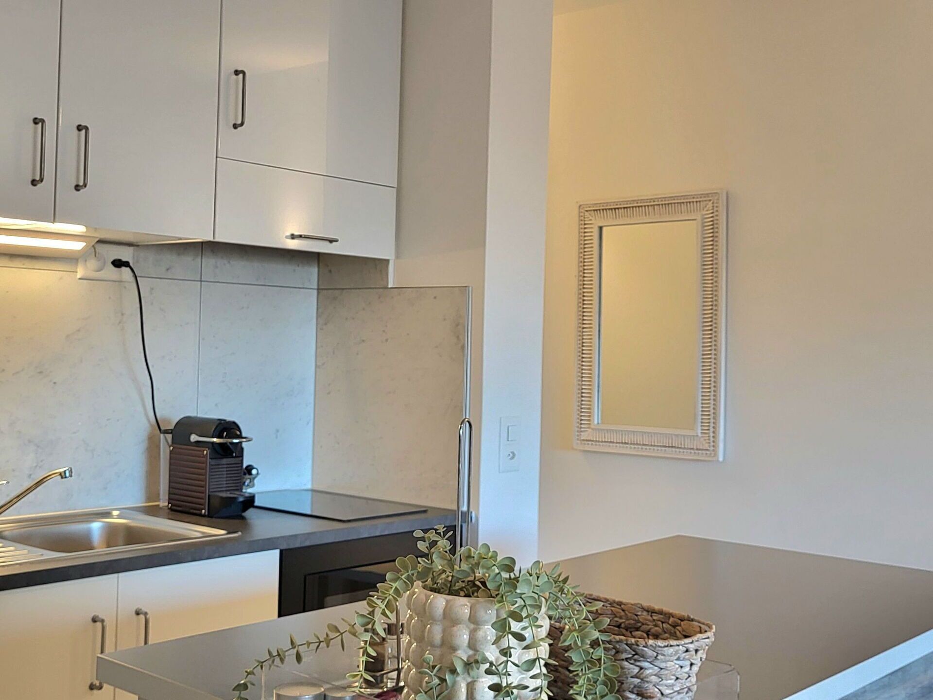 A modern kitchen with white cabinets, a stainless steel sink, and a built-in stove.