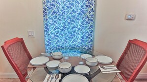 Une table à manger dressée avec des assiettes, des bols et des couverts, entourée de chaises en osier.