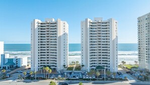 Un hotel di grandi dimensioni con numerosi piani, un parcheggio e vista sull'oceano.