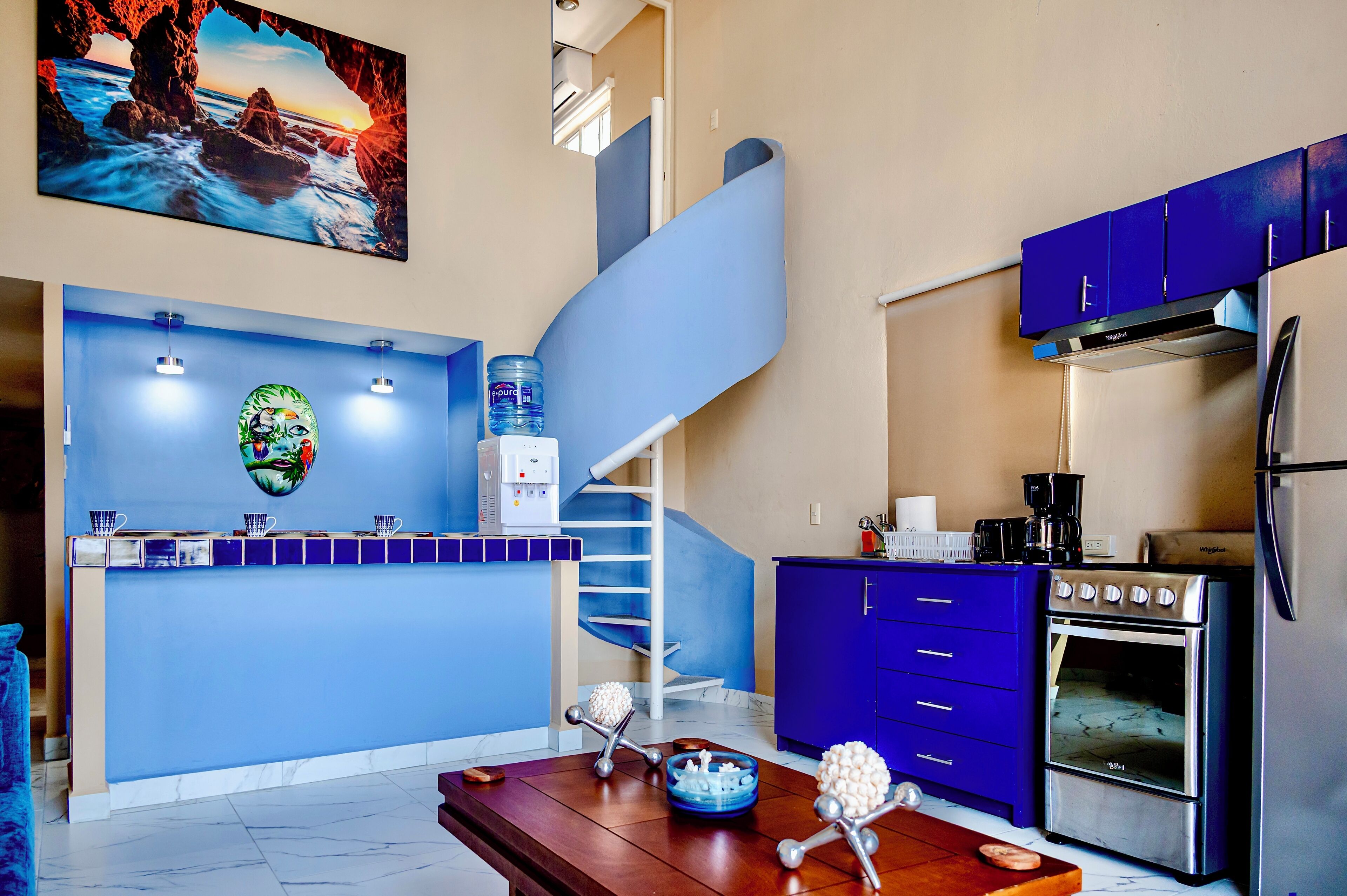 Een moderne keuken met een blauwe accentmuur, een roestvrijstalen oven en een waterdispenser.