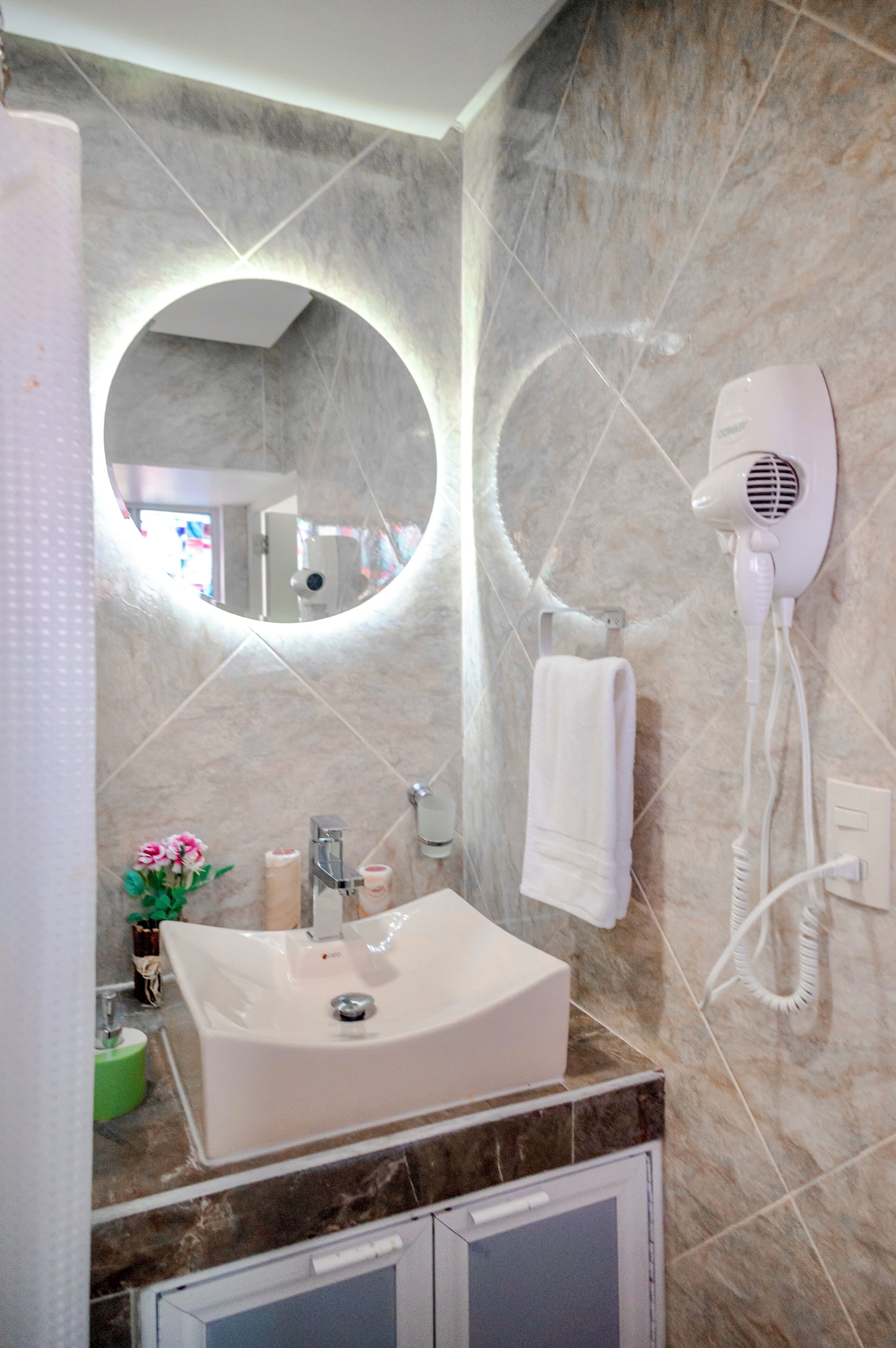 Une salle de bain équipée d’un lavabo, d’un miroir, d’un sèche-cheveux et d’un porte-serviettes.