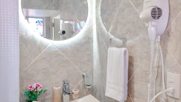 Une salle de bain équipée d’un lavabo, d’un miroir, d’un sèche-cheveux et d’un porte-serviettes.