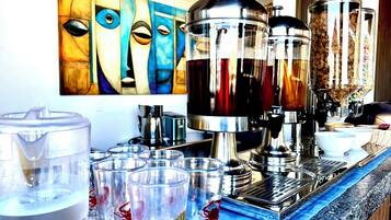 En bardisk med en kaffemaskin, glas och en tavla på väggen.