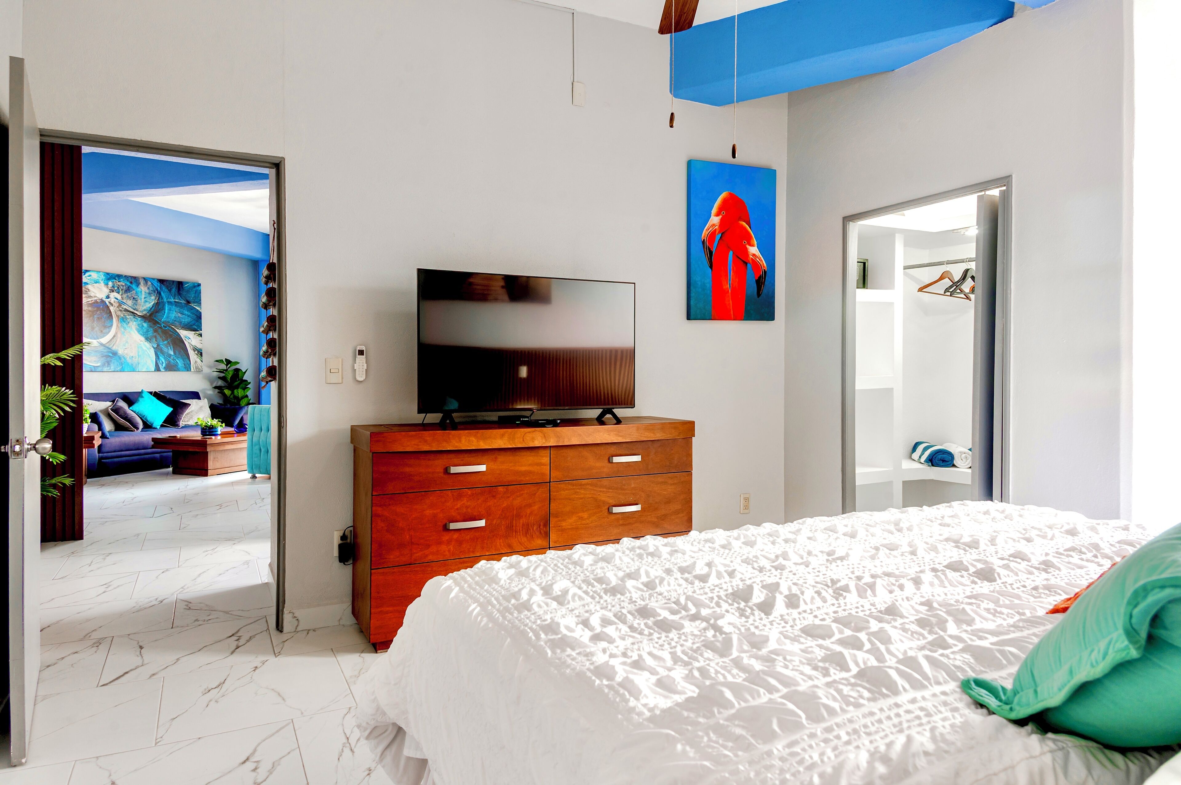 Una camera da letto con un letto grande, una cassettiera in legno, una televisione a schermo piatto e un quadro appeso al muro.