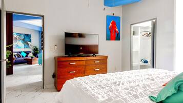 Una camera da letto con un letto grande, una cassettiera in legno, una televisione a schermo piatto e un quadro appeso al muro.