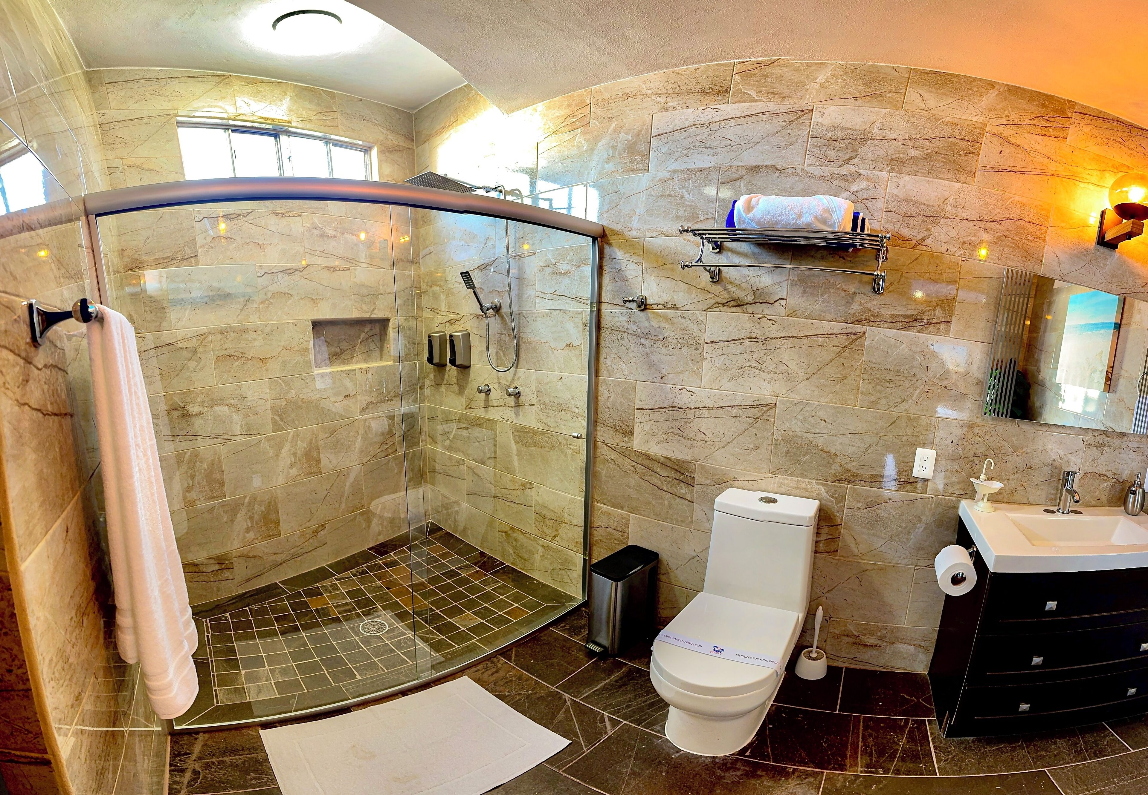 A modern bathroom with a glass-enclosed shower, a toilet, and a sink.