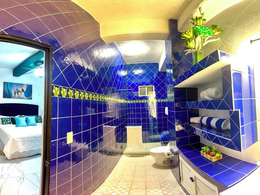 Ein Badezimmer mit blauen Fliesen, Toilette, Waschbecken und Duschbereich.