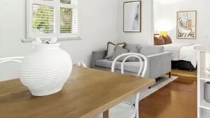 Ein modernes Wohnzimmer mit Holztisch, weißem Sofa und einer großen weißen Vase.
