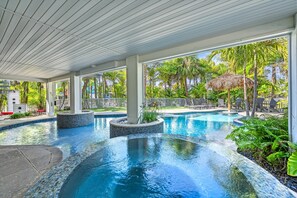 Una piscina con borde de azulejos, rodeada de sillas de descanso y palmeras.