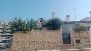 A stone wall with a gate, a building with a tiled roof, and a satellite dish. - STUDIO APARTMENT IN DENIA—MARINA (IBIZA) (DENIA)