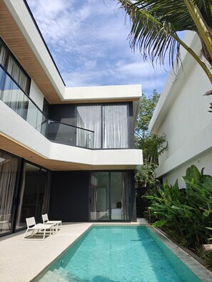 Een modern herenhuis met zwembad, grote ramen en een balkon.