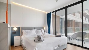 Een moderne hotelkamer met een groot bed, een nachtkastje, een wandlamp en uitzicht op het balkon.