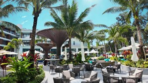 Een resort binnenplaats met buitenmeubilair, palmbomen en een zwembad.