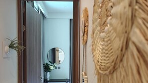 Ein Flur mit Holztür, Spiegel und Wandbehagung aus Makramee.