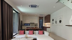 Ein modernes Wohnzimmer mit einer Sofagarnitur, zwei runden Couchtischen und Blick zur Küche.