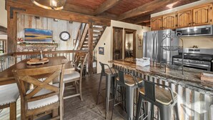 Una cocina rústica con vigas de madera, una chimenea de piedra y una isla grande con taburetes de bar.