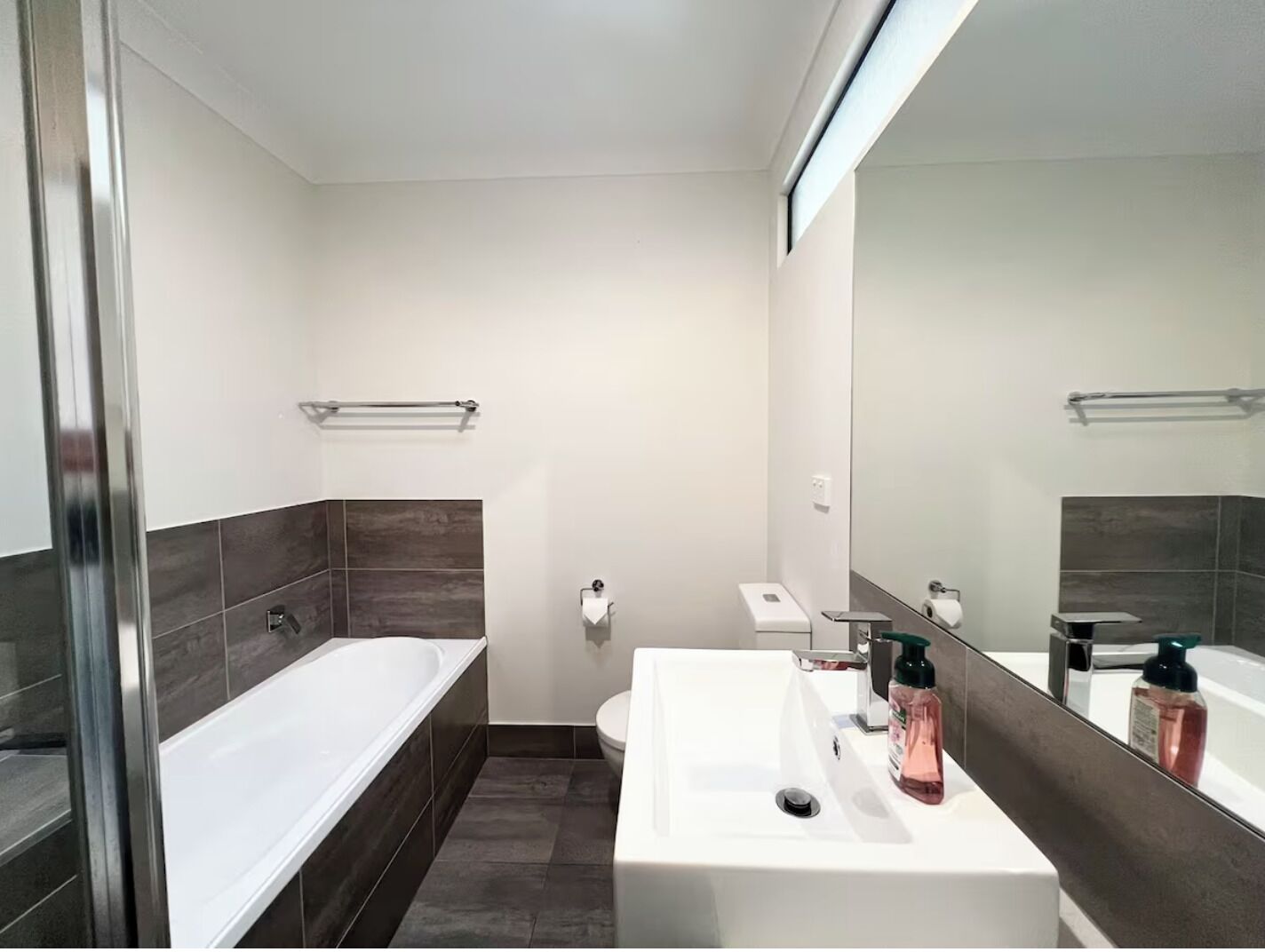 A modern bathroom with a bathtub, a sink, and a toilet.